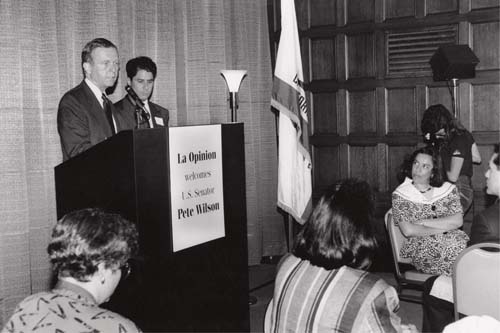 Antonia Hernandez, right, at the time president and general counsel of the Mexican American Legal Defense and Educational Fund (MALDEF), looks on as future Gov. Pete Wilson addresses staff of La Opinión in September 1990. 